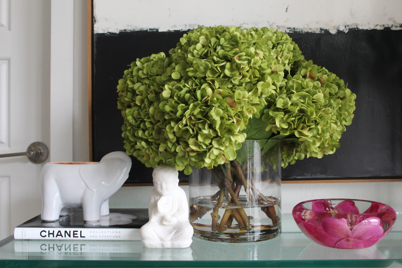 Bouquet d'hortensias verts dans un vase cylindrique en verre transparent